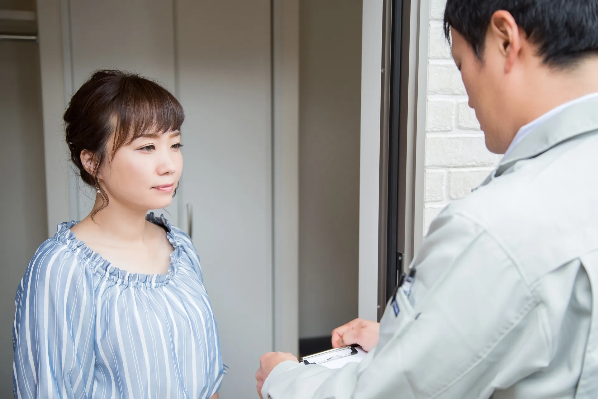 屋根修理業者の飛び込み営業で訪問する作業服の男性